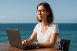 A digital nomad working on a laptop at a beach, showcasing freedom and flexibility.